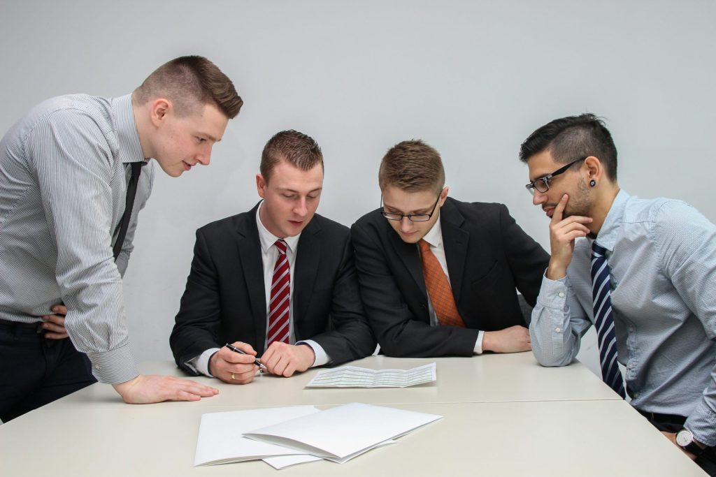 Cuatro hombres en una reunión mirando papeles